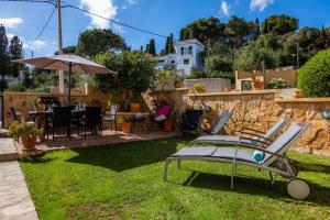 a group of chairs and an umbrella in a yard at Apartamento La Pergola in Font de Sa Cala