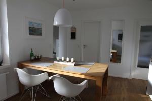 a dining room with a wooden table and white chairs at Ferienwohnung Strandgut in Glücksburg