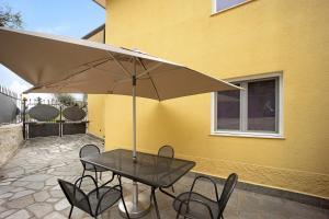 a table and chairs under an umbrella on a patio at Appartamento La Buraggia in Diano San Pietro
