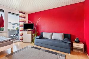 a living room with a couch and a red wall at Szafranzimmervermietung in Winnenden