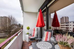 a balcony with two red umbrellas and a table and chairs at Szafranzimmervermietung in Winnenden
