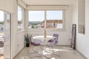 a dining room with a white table and purple chairs at Apartamento ático en L'Escala in L'Escala