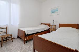 two beds in a small room with a chair and a window at Quadrilocale Via D'annunzio in San Teodoro