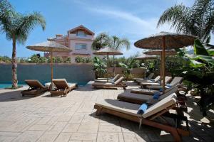 a group of lounge chairs and umbrellas next to a pool at Villa Dionysia Studio S2 in Alikanas