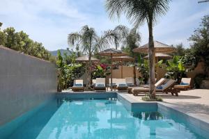 a swimming pool with chairs and umbrellas at Villa Dionysia Studio S2 in Alikanas