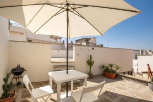 a white table and chairs and an umbrella on a roof at Leonardò, non solo mare in Nardò