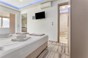 a white bedroom with a large bed and a tv at Villa Dionysia Studio S2 in Alikanas