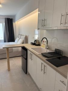 a kitchen with white cabinets and a bed in a room at Nice & cosy central studios in Mikonos