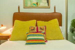 a bed with two pillows and a colorful crochet pillow at Flamingo Rosa in Arinaga