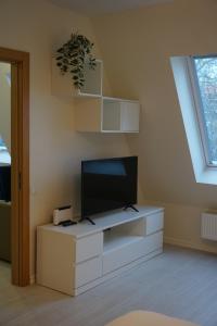 a living room with a tv on a white cabinet at Kaiju Apartment 15 in Liepāja