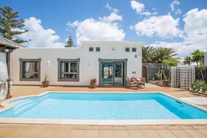 a villa with a swimming pool in front of a house at Villa Capricho in Lanzarote
