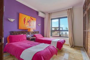 two beds in a room with purple walls and a window at Villa Capricho in Lanzarote +18 photos
