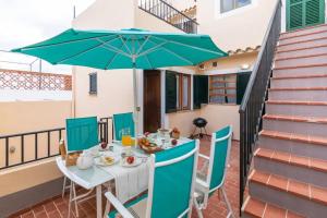 a table and chairs with an umbrella on a balcony at Puig in Pollença