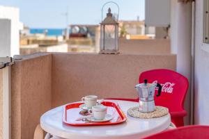 a table with two cups and a coffee maker on it at Casa Riviera in Donnalucata
