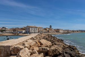 a rocky shoreline with houses and the ocean at Casa Riviera in Donnalucata