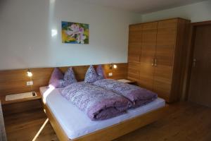 a bedroom with a large bed with purple pillows at Waalhof Ferienwohnung Apfelblüte in Silandro +27 photos