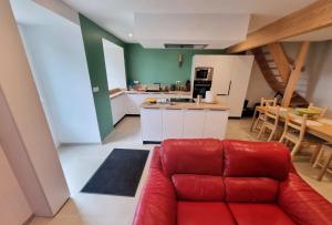 a living room with a red couch and a kitchen at L'Ecole Buissonnière de Mazalibrand in Mazet-Saint-Voy