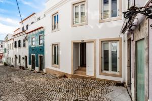 a street with white buildings on a cobblestone road at Beach House In Sesimbra in Sesimbra
