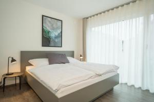 a white bedroom with a bed and a window at Ferienwohnung Arguna in Langenargen