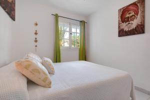 a bedroom with a bed with white sheets and a window at Casa Isa in El Cotillo