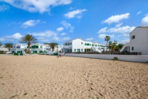 a sandy beach with white buildings and palm trees at Casa Isa in El Cotillo