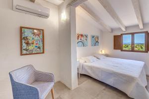 a white bedroom with a bed and a chair at Son del Rio Vell in Pollença +18 photos