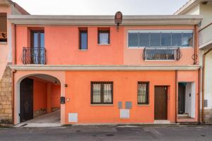 an orange building with an entry way and a balcony at Villa Gloma in Capoterra