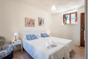 a white bedroom with a bed with towels on it at Can Xeliu in Sóller +17 photos