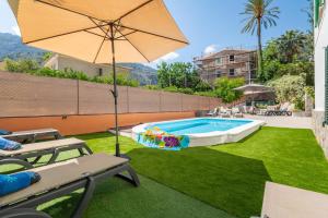 a swimming pool with an umbrella and a lawn at Can Xeliu in Sóller