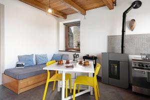 a small kitchen with a table and yellow chairs at Nature House Custu Giancu in Cichero