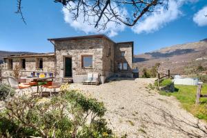 a stone house on a hill with a table and chairs at Nature House Custu Giancu in Cichero