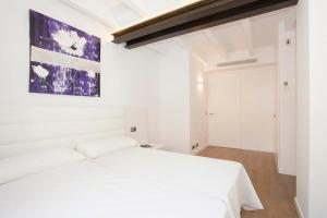 a bedroom with a white bed and a painting on the wall at Casa Sant Sebastia in Pollença +14 photos