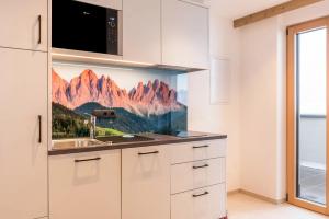 a kitchen with a sink and a microwave at Planerhof Apartment Edelweiss in Funes +17 photos