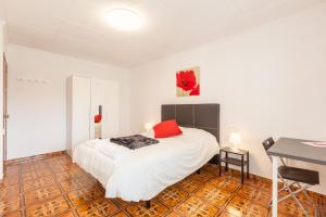 a bedroom with a white bed with red pillows on it at Apartamento Villa Mercedes in Rubí