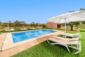 a pool with two lounge chairs and an umbrella at Casa Campillos in Llucmajor