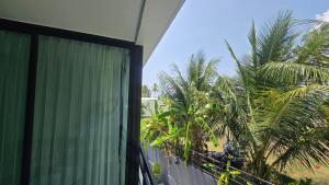a balcony of a house with palm trees at joyful the Kris202 in Ban Lum Fuang
