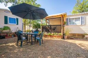a table and chairs with an umbrella in a yard at Salamandre in Sainte-Croix-de-Verdon