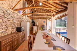 a dining room with a long table and a stone wall at Casa Juan y Loli in Nigüelas