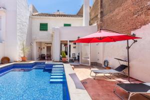 a house with a swimming pool with a red umbrella at Casa Juan y Loli in Nigüelas