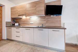 a kitchen with a sink and a tv on the wall at Heiserhof App Holunder in Racines +11 photos