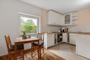 a kitchen with white cabinets and a table and a window at Nichtraucher-Ferienwohnung Sandhaas in Ringsheim +12 photos