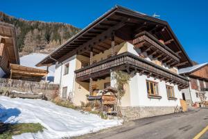 a house with a wooden roof in the snow at Heiserhof App Holunder in Racines