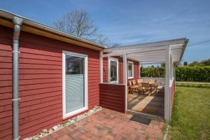 ein rotes Haus mit Veranda und Terrasse in der Unterkunft Holtdeel in Gelting