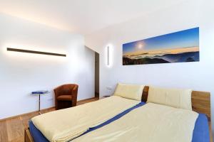 a white bedroom with a bed and a chair at Wolf's Apartment Schwarzwald in Renchen