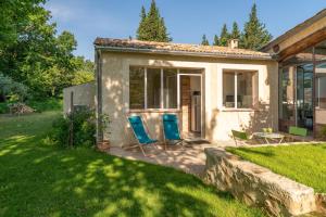 a house with two blue chairs in a yard at Studio à la campagne in Sarrians