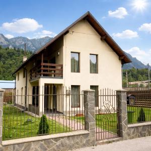 a house with a fence in front of it at Casa Aly Bușteni- Casa la cheie in Buşteni