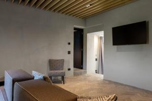 a living room with a couch and a tv on the wall at Suite Cantina in San Gimignano