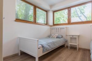 a small bedroom with a bed and two windows at Casa Weekend in Revò