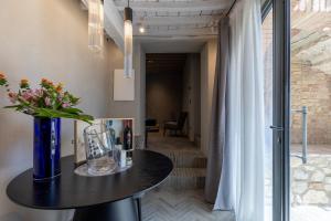 a black table with a vase of flowers on it at Suite Cantina in San Gimignano +19 photos