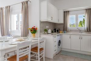 a kitchen with white cabinets and a white table and chairs at Afroditi Ftelia Anemone in Mykonos +15 photos